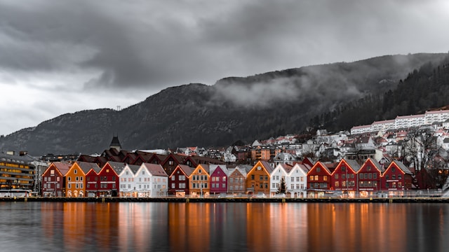 Bryggen in Bergen, Norway – colorful wooden buildings along the waterfront with mountains and mist in the background.